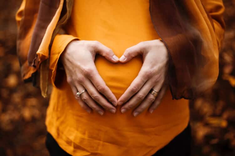 Pregnant woman with her hands on ther belly in a heart shape