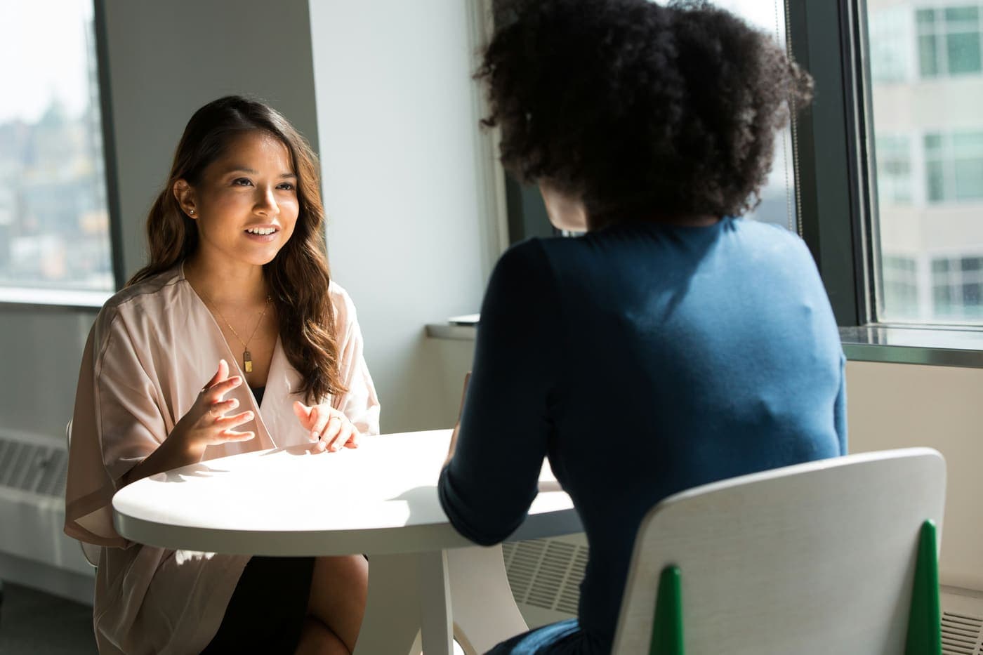 Two colleagues in a calm one-on-one conversation at a workplace table